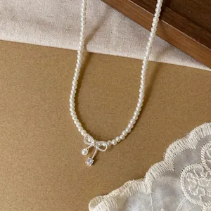 Macro view of an elegant white pearl necklace featuring a bow and zircon pendant