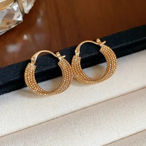 Detailed macro shot of textured 18k gold plated hoop earrings on velvet