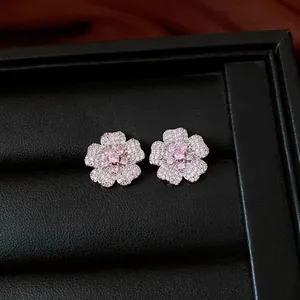 Detailed view of elegant flower stud earrings with pink and white zircons in a box.