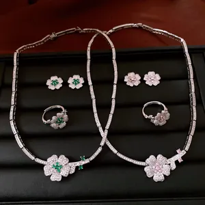 High-detail macro view of zircon flower jewelry sets in green and pink on black velvet display