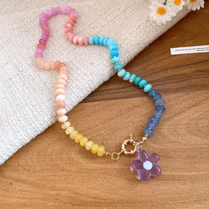 Primo piano di una collana di perle colorate con un ciondolo a fiore viola trasparente