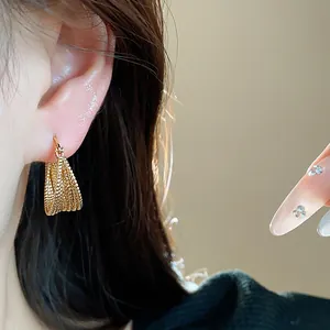 Close-up shot of an 18k gold plated minimalist textured hoop earring worn on a person's ear