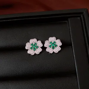 Macro view of flower-shaped stud earrings featuring green gemstones and white zircon