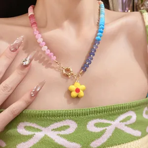 Primo piano di una collana di perle colorate con un ciondolo a fiore giallo su una modella