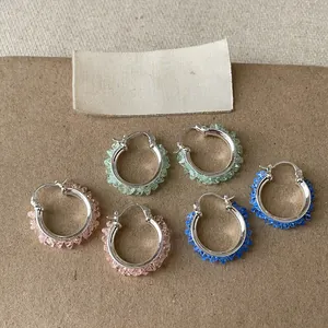 Nahaufnahme bunter Creolen mit Glassteinen in Rosa, Grün und Blau für stilvolle Damen.
