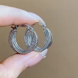 Close-up macro view of silver-tone hoop earrings with intricate beaded texture