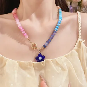 Primo piano di una collana di perle colorate in stile dopamina con ciondolo a fiore blu.