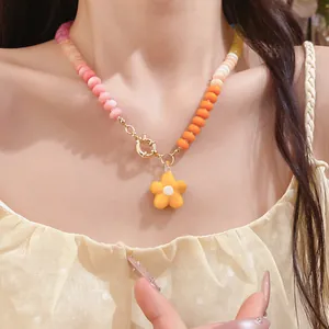 Dettaglio di collana di perline colorate con ciondolo a fiore giallo indossata da una modella