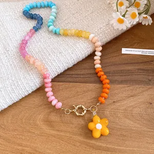 Dettaglio di una collana a perle colorate con ciondolo a fiore giallo in stile dopamina