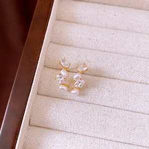 Macro detail of French style gold earrings featuring oval pearls and cubic zirconia stones