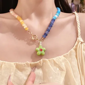 Dettaglio ravvicinato di una collana di perline sfumate colorate con ciondolo a fiore verde su modella