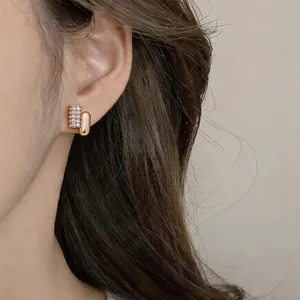 Close-up detail shot of elegant gold oval stud earring with paved cubic zirconia stones