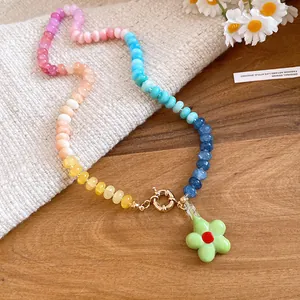Primo piano di una collana di perle colorate con ciondolo a fiore verde su legno