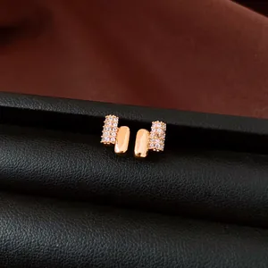 Close-up detail of gold-plated geometric stud earrings featuring sparkling pavé zircon stones
