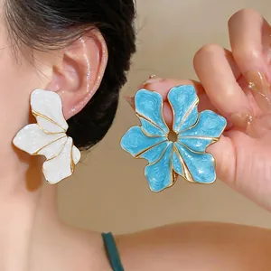 Detail showing the textured enamel finish and gold-tone edges of large flower earrings.