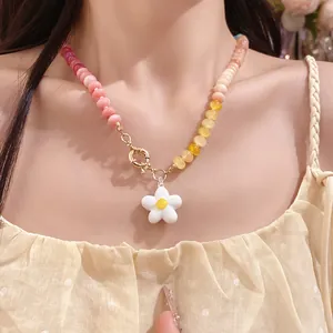 Dettaglio di una collana di perle colorate con ciondolo a fiore bianco su una modella