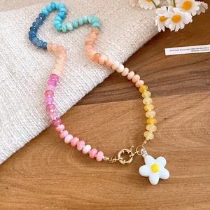 Primo piano di collana di perle colorate con ciondolo a fiore bianco e chiusura dorata
