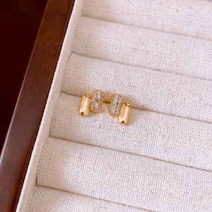 Detailed macro shot of elegant gold-toned geometric stud earrings with pave zircons.