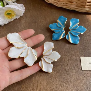 Detailed macro view of stylish drip oil petal earrings in white and blue finishes