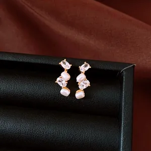 Close-up of elegant gold plated earrings with oval zirconia and pearls (81 chars)