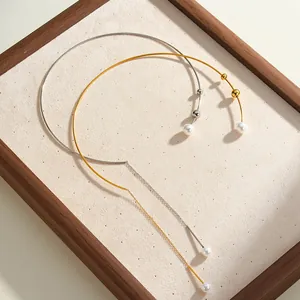 Dettaglio ravvicinato di eleganti girocolli in acciaio oro e argento con perle