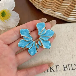 Detailed view of oversized blue enamel petal earrings featuring elegant gold metallic trim