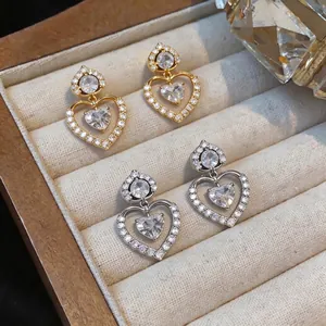 Elegant heart-shaped zircon stud earrings in gold and silver finishes on a velvet tray