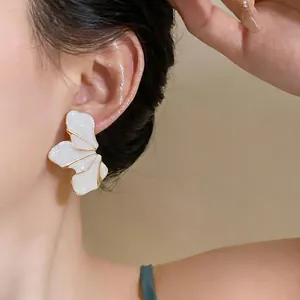 Elegant white enamel petal stud earring with gold metal trim shown on model's ear