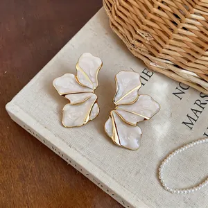 Close-up detail of exquisite petal stud earrings with cream marble texture and gold metal edges