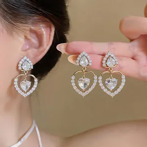 Detailed close-up view of 18k gold plated heart-shaped drop earrings with sparkling zircons