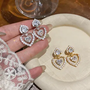 Close-up of 18k gold plated zircon heart stud earrings with sparkling crystal details.