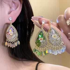 Detailopname van bohemian druppeloorbellen met bloemen, kwastjes, strass en gekleurde kralen.