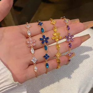 Close-up of elegant gold-tone bracelets with colorful zircon flower charms