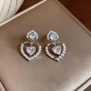 Macro detail of elegant silver-tone heart drop earrings with sparkling heart-shaped zircon stones