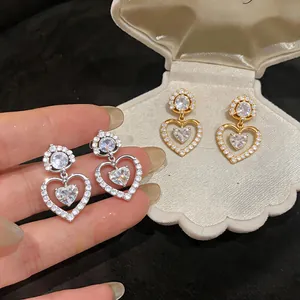 Detailed macro view of heart-shaped zircon earrings in silver and gold-plated finishes