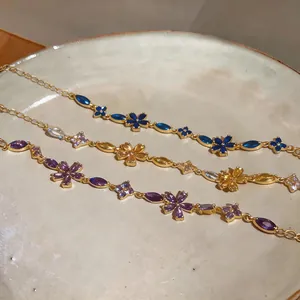 Detail of three flower zircon bracelets in purple, gold, and blue on a ceramic plate