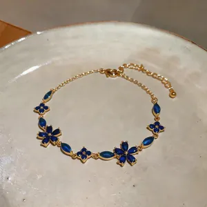 Detail view of blue floral zircon bracelet with delicate gold chain and adjustable clasp