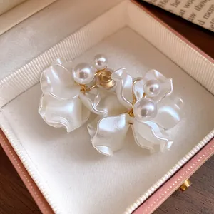 Detailed macro view of elegant white petal clip-on earrings decorated with glossy pearl accents