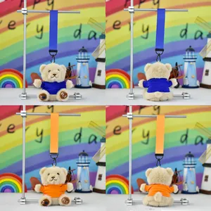 Detail view of mini plush teddy bear keychains in blue and orange shirts with foot embroidery