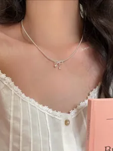 Nahaufnahme einer eleganten Perlenkette mit Schleife am Hals für einen zarten Look