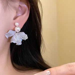 Detailed view of elegant pearl and white flower petal earrings on an Asian model