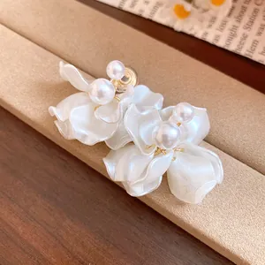 Detailed view of elegant pearl flower petal earrings with a glossy white finish
