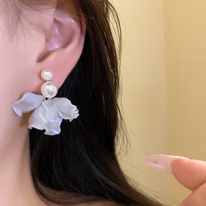 Close-up detail of elegant white pearl flower petal clip-on earrings being worn.