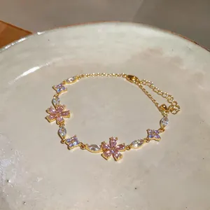 Exquisite close-up detail of a gold chain bracelet with pink and clear zircon flowers