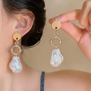 Detail view of French Baroque irregular pearl drop earrings with gold metal accents.