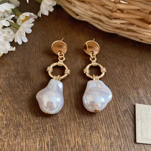 Detailed macro view of irregular baroque pearl earrings with golden circular metal accents