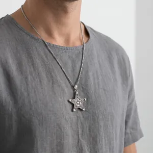 Close-up of a men's vintage stainless steel star pendant necklace on a grey shirt.