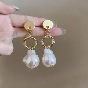 Detailed view of French baroque irregular pearl drop earrings with golden rings and crystals.