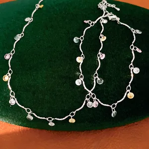 Macro view of silver necklace with colorful round zircon stones on green velvet