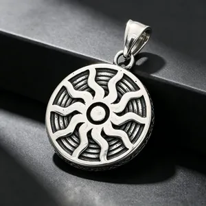 Macro detail of a vintage stainless steel round pendant with radial sun pattern engraving